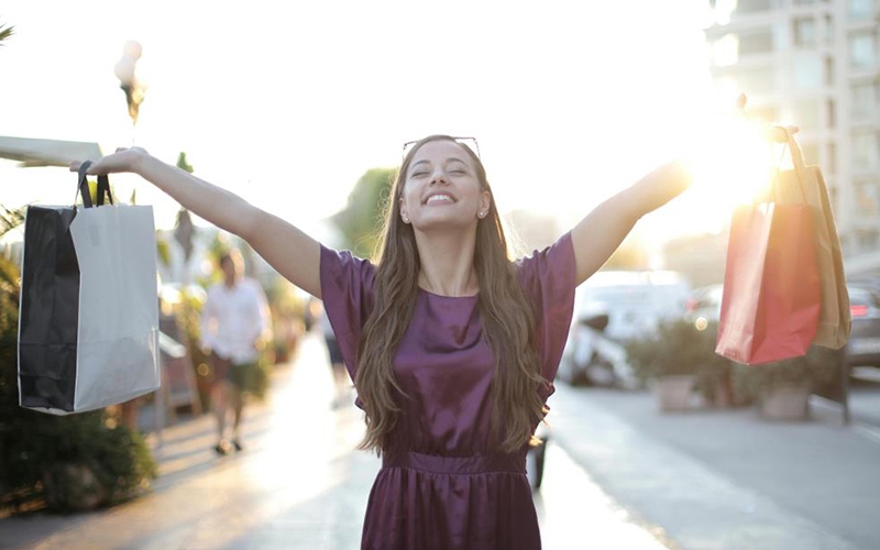 Woman with her arms outstretched holding shopping bags